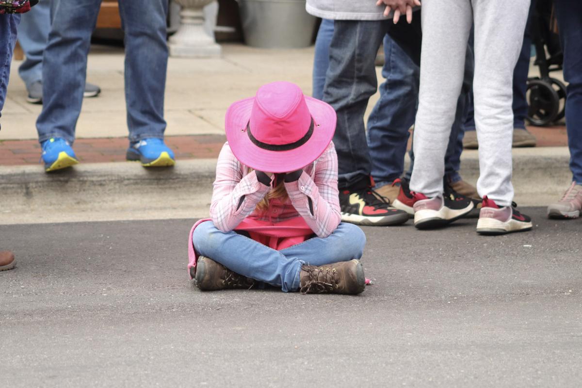 Little girl with cowboy hat sitting in street
